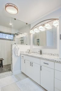 large white modern bathroom with granite countertop and tiled shower
